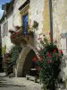 Monpazier - Casa en lugar de ángulos (plaza central de la mansión) con rosales trepadores (rosas rojas) y un balcón decorado con flores, en el Périgord