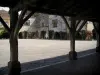 Monpazier - Pilares de madera de la sala de vistas a las casas con fachadas decoradas con rosas trepadoras y las arcadas de los ángulos de la Place des (plaza central de la mansión), en el Périgord