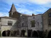 Monpazier - Casas de frente adornada con rosas trepadoras y las arcadas de los ángulos de la Place des (plaza central de la mansión), y la torre de la iglesia, en el Périgord
