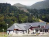 Le Mont-Dore - Station de ski : bâtiment, terrasse de café et arbres ; dans le massif du Sancy (monts Dore), dans le Parc Naturel Régional des Volcans d'Auvergne