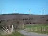 Montagne Noire - Éoliennes, forêt et petite route bordée de prés clôturés