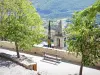 Montbrun-les-Bains - Banc entouré d'arbres avec vue sur le clocher d'église et le paysage verdoyant alentour