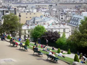 Montmartre - Ruhepause auf den Sitzbänken und Rasenflächen des Gartens der Sacré-Coeur, mit Blick auf die Gebäude von Paris