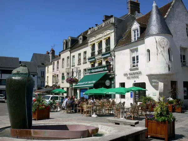 Mortagne-au-Perche - Place du Général de Gaulle : façades de maisons, terrasse de café, fontaine et fleurs ; dans le Parc Naturel Régional du Perche