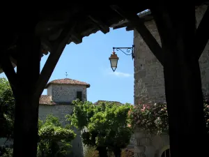 Mortemart - Pfeiler der Hallen vorne, mit Blick auf das Schloß der Ducs und ein blumengeschmücktes Haus des Dorfes