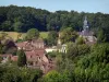 Moutiers-au-Perche - View of the bell tower of the Notre-Dame du Mont-Harou church and houses of the village surrounded by trees; in Perche Regional Nature Park