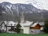 Névache - Torre sineira da igreja de Saint-Marcellin e casas da aldeia, árvores e montanhas cobertas de neve; no Vale do Clarée