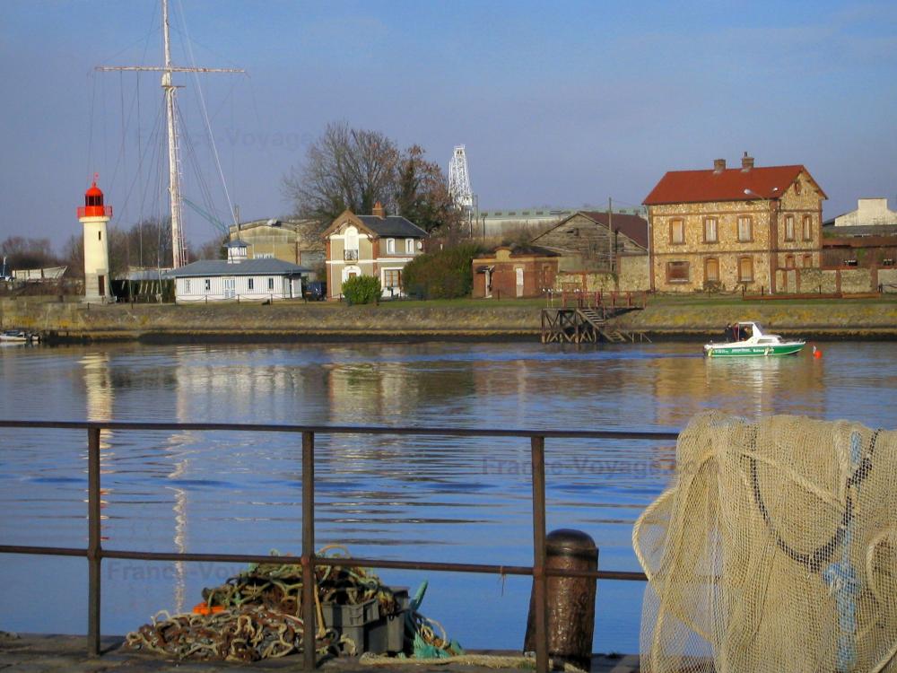Guide de la Normandie - Honfleur - Filet de pêche suspendu à une rambarde, avant-port (port de pêche), bateau naviguant, maisons, phare et mât des signaux