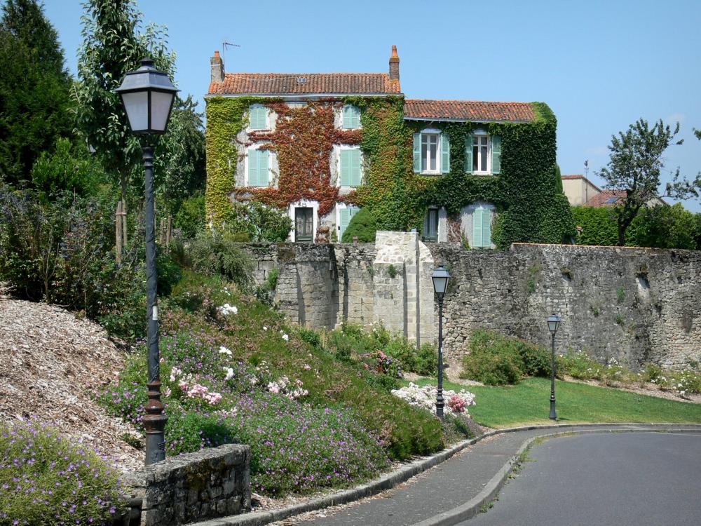 Guide de Nouvelle-Aquitaine - Parthenay - Maison couverte de vigne vierge, remparts, lampadaires et massifs de fleurs de la ville médiévale