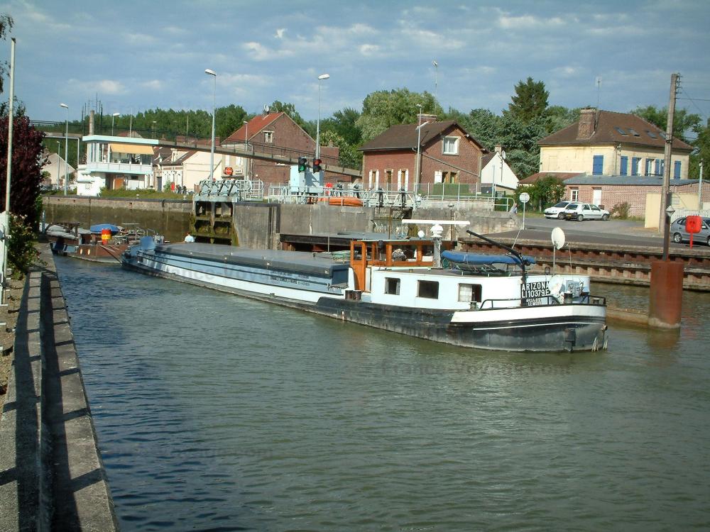 Guide de l'Oise - Cité des Bateliers - À Longueil-Annel : péniche naviguant sur le canal latéral à l'Oise, berges et maisons