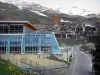 Orcières-Merlette - Orcières 1850: sporting arena made of glass (modern architecture), road and buildings of the ski resort (winter and summer sports resort), mountains with snowy summits (snow); in Champsaur