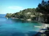 Paisagens da costa da Riviera Francesa - Cabo com praia, pequeno pontão, mar azul-turquesa, pequeno barco e pinhal