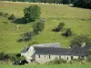 Paisagens do Mayenne - Pedra fazenda rodeada por prados e vaca descansando na grama em primeiro plano