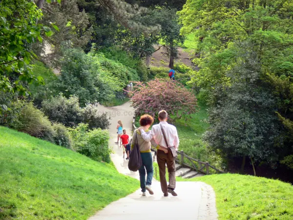 Parc des Buttes-Chaumont - Couple de promeneurs arpentant une allée en pente du parc paysager