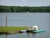 Paysages de la Sarthe - Lac de Sillé, dans le Parc Naturel Régional Normandie-Maine : plan d'eau, pédalo amarré, et forêt de Sillé en arrière-plan