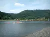 Paysages des Vosges - Rive, lac avec kayaks et bateaux, arbres (forêt) en arrière-plan et nuages dans le ciel