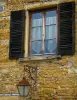 Pierres Dorées (golden stones) area - Facade of a stone house with window, wooden shutters and lamppost