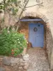 Pigna - La entrada a una casa con sus puertas azules, flores y un árbol de higo (en Balagne)