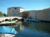 Port-Grimaud - Bateaux amarrés en premier plan et pont menant à la porte de la cité lacustre