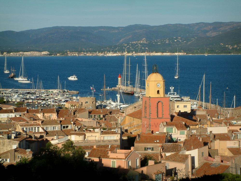 Guide de Provence-Alpes-Côte d'Azur - Saint-Tropez - Vue sur le clocher de l'église, les toits des maisons de la vieille ville, le port, les bateaux, les voiliers, la mer méditerranée et les collines