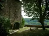 Puycelsi - Stenen huis en tuin met een boom en een bankje met uitzicht op het bos Gresigne