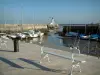 Ré island - La Flotte: quay and bench in foreground with view of boats at ebb tide and the lighthouse in the port