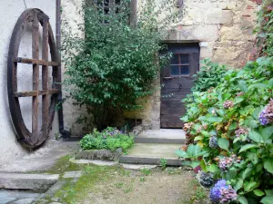 Richard de Bas Mill - Local da fábrica de papel: porta de entrada de um prédio e arbustos em flor; na comuna de Ambert, no Parque Natural Regional Livradois-Forez