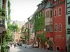 Riquewihr - Rue principale (rue du Général-de-Gaulle) : demeure avec un oriel, maisons colorées ornées de fleurs et de plantes grimpantes, terrasses de cafés