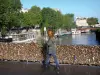 Rives de la Seine - Pont de l'Archevêché et sa rambarde recouverte de cadenas d'amour, avec vue sur la Seine, les péniches amarrées au quai de Montebello, le pont au Double et les façades d'immeubles du quartier latin