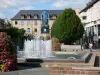 Rodez - Springbrunnen, Blumendekorationen und Fassade der Galerie Sainte-Catherine im Hintergrund