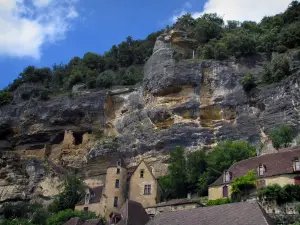 La Roque-Gageac - Maisons du village, dont le manoir de Tarde, et fort troglodytique dominant l'ensemble, nuages dans le ciel bleu ; dans la vallée de la Dordogne, en Périgord