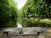Royaumont abbey - Canal lined with trees and stone bench at the edge of the water; in the town of Asnières-sur-Oise, in the Oise-Pays de France Regional Nature Park
