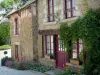 Saint-Céneri-le-Gérei - Fachada de uma casa de pedra forrada com flores