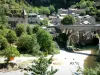 Saint-Chély-du-Tarn - Puente sobre el río Tarn, cerca de la torre de la iglesia de Nuestra Señora de la Asunción, los árboles y las casas de la aldea en la ciudad de Sainte-Enimie, en el corazón de las Gargantas del Tarn, en el Parque Nacional de Cévennes