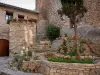 Saint-Guilhem-le-Désert - Oude kerk van St Lawrence herbergt het VVV-kantoor (rechts), stenen huis, boom en bloemen