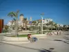 Saint-Raphaël - Esplanade agrémentée de palmiers et de bancs avec vue sur le Casino, l'église (basilique) Notre-Dame-de-la-Victoire-de-Lépante de style néo-byzantin et les immeubles de la station balnéaire
