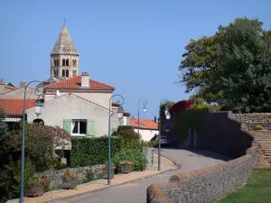 Saint-Saturnin - Zweistöckiger, achteckiger Kirchturm der romanischen Kirche Saint-Saturnin, Strasse gesäumt von Strassenleuchten und Häuser des mittelalterlichen Dorfes