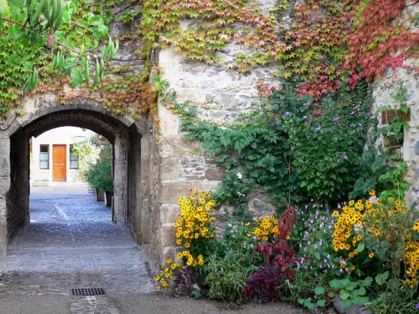 Sainte-Eulalie-d'Olt - Überwölbter Durchgang und Blumendekorationen der mittelalterlichen Stätte