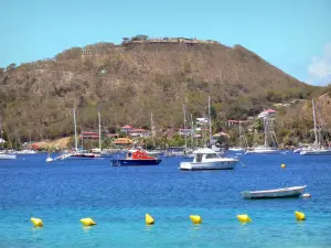 Les Saintes - Saintes bahía con barcos, casas de Terre -de - Haut, y el Fuerte de Napoleón en la parte superior de la colina Mire