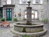 Salers - Fontaine et façade fleurie d'une maison en pierre