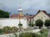 Salins-les-Bains - Dôme et lanternon de la chapelle Notre-Dame-Libératrice, allée bordée de fleurs, arbres et maisons de la ville thermale
