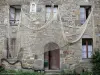 São Sulíaco - Fachada de uma casa de pedra decorada com uma rede de pesca