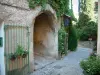 Séguret - Ruelle pavée avec un passage voûté et une maison ornée de rosiers, de plantes et de fleurs