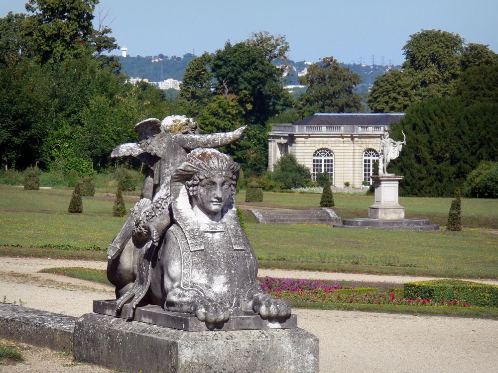 Guide de la Seine-et-Marne - Château de Champs-sur-Marne - Parc du château : statue de sphinx en premier plan, parterres de fleurs, pelouses, arbustes, orangerie et arbres