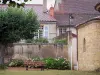 Semur-en-Brionnais - Giardino con una panchina, un albero e fiori, chiesa di Saint-Hilaire (chiesa) e le case nel villaggio, in Brionnais