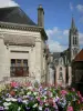 Sille-ле-Гийом - Цветы на переднем плане с видом на колокольню церкви Нотр-Дам и фасады домов в городе