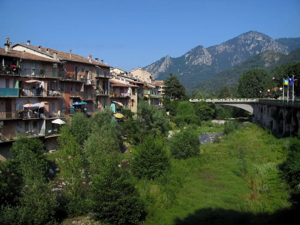 Sospel - Maisons du village médiéval au bord de la rivière Bévéra, arbres au bord de l'eau, pont et montagnes