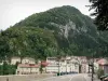 St. Claude - Poste de luz da Grande Ponte, casas e prédios da cidade e montanhas cobertas de árvores; no Parque Natural Regional do Haut-Jura