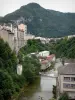 St. Claude - Passarela que atravessa o rio, árvores à beira da água, casas e prédios da cidade e montanhas; no Parque Natural Regional do Haut-Jura