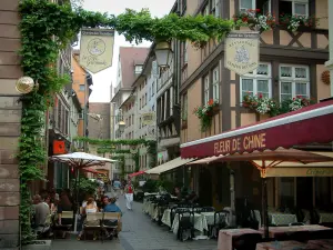 Strasbourg - Coopers barrio: calle con casas con flores y restaurantes al aire libre